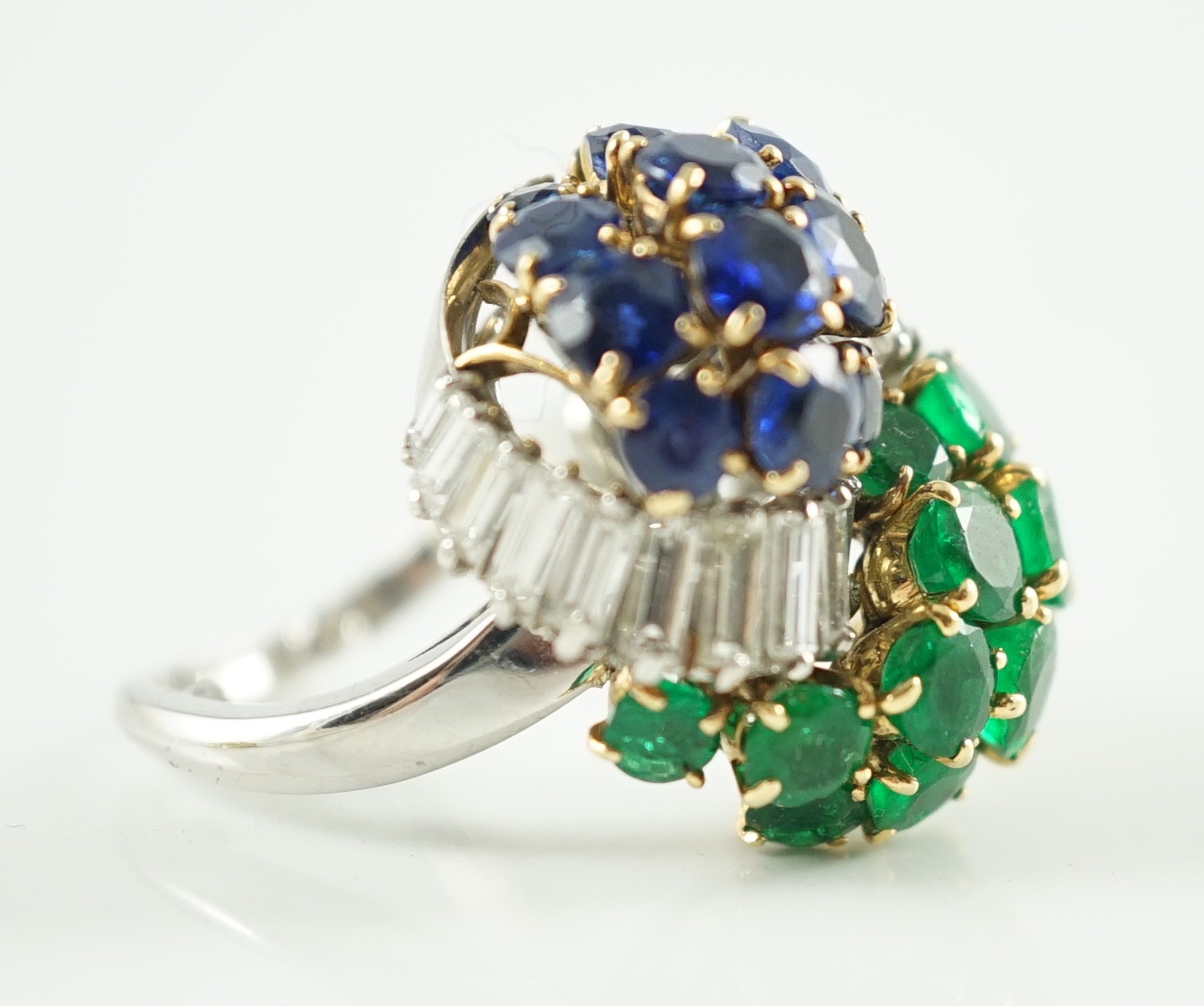 A mid 20th century French 18ct white gold round cut emerald, sapphire and graduated baguette cut diamond cluster set 'Yin-Yang' dress ring, by Mauboussin, Paris